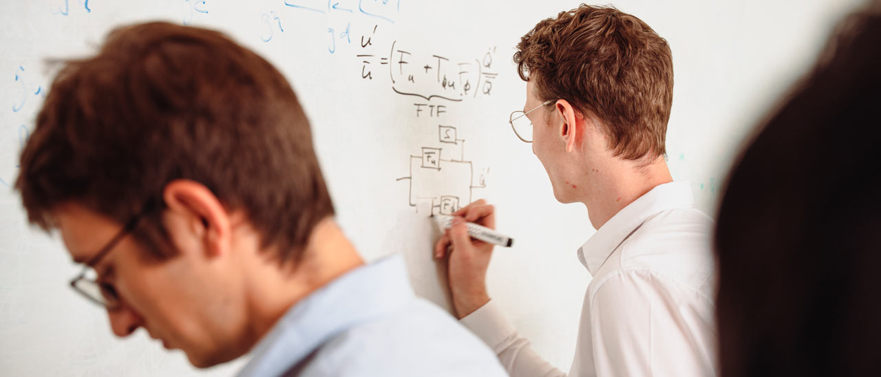 A scientist writes a formula on the whiteboard