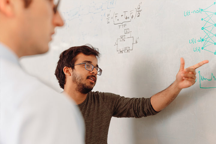 a researcher points to a formula on the whiteboard